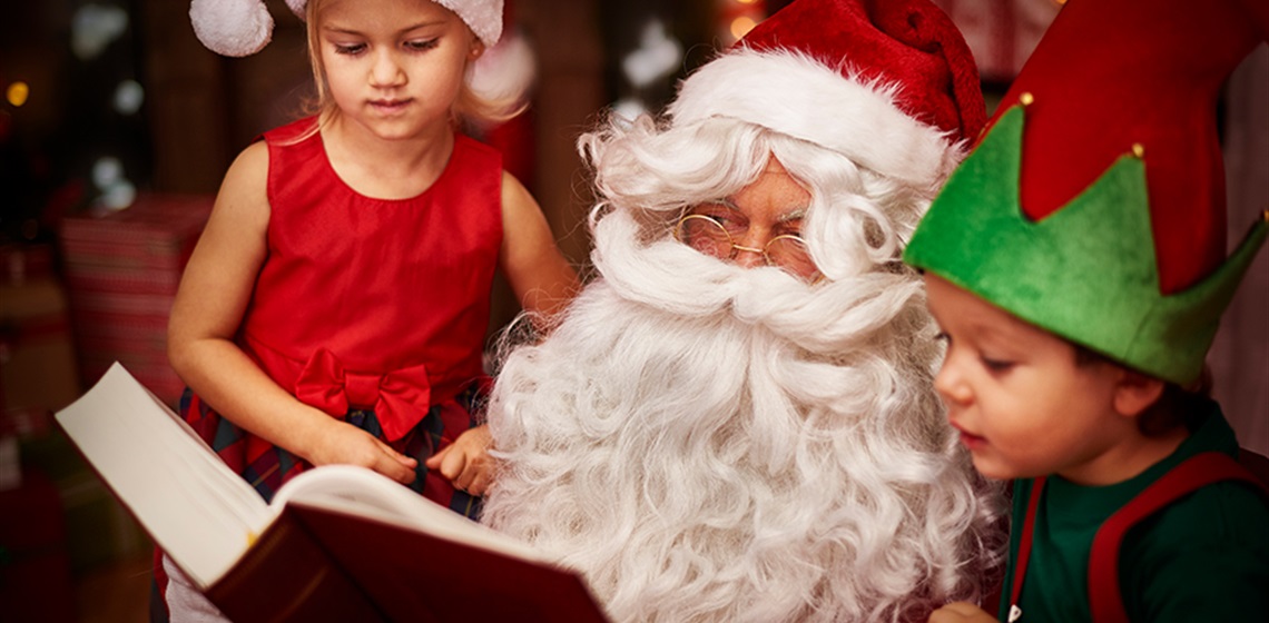 IMage of Santa reading a story to a young boy and girl.