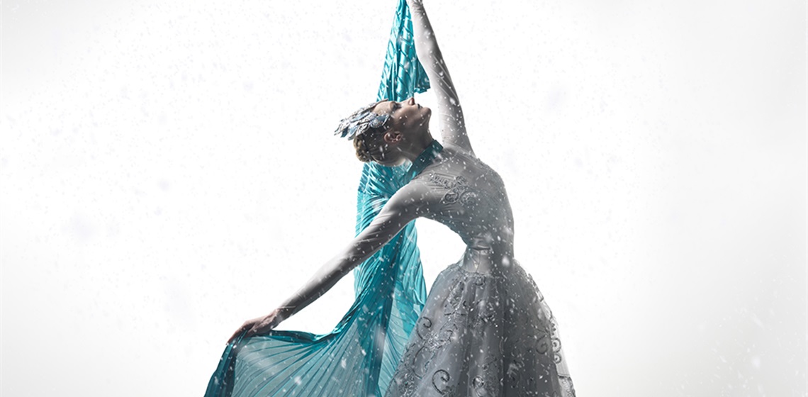 Image of a ballerina from the cast of The Snow Queen with one arm outstretched behind her and her other arm reaching for the sky.